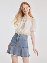 A lady wears a shirt and a pleated skirt.